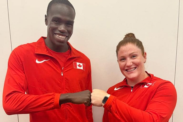 marco arop and sarah mitton bumping fists and smiling for the camera wearing red team canada shirts