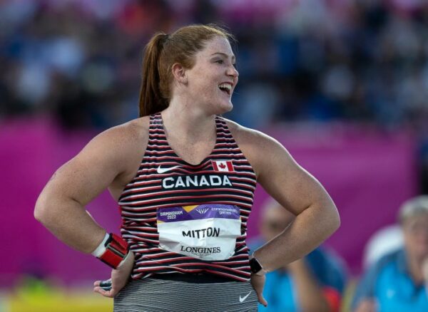 sarah mitton with her hands on her hips laughing wearing the team canada uniform at the commonwealth games