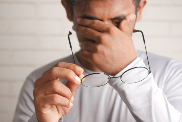 Man rubbing eyes while hlding eyeglasses
