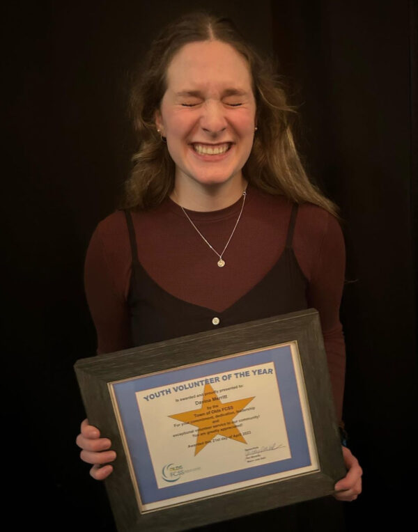 Young woman holding an award plaque for youth volunteer of the year from Olds, Alberta