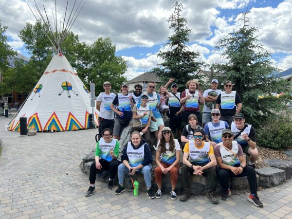 group of students posed outdoors in front of a teepee.