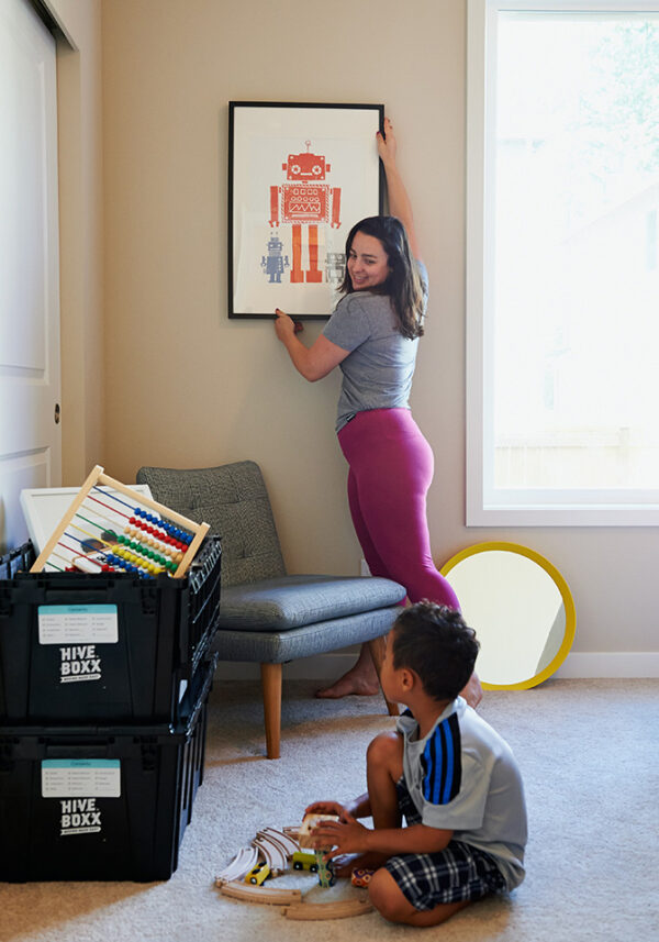Young mom hangin a picture with her son looking on