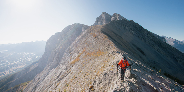 Hiker in red coat on top of mountain peak
