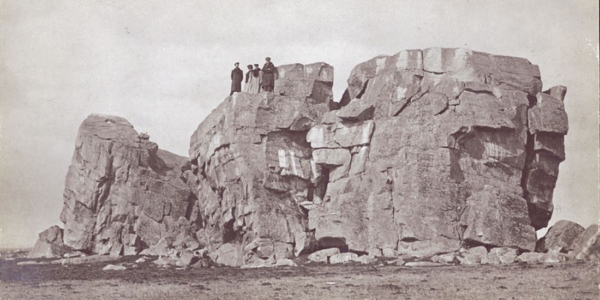 Four men standing at the top of the Big Rock at Okotoks, Alberta, ca. 1920.
