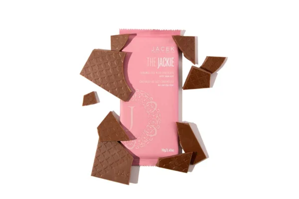 A broken chocolate bar overtop of another chocolate bar in a pink wrapper.